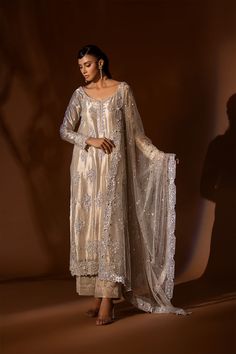 White Silk Salwar Kameez Pakistani Wedding Dresses come in a long gold tissue shirt with heavily embellished motifs and gangajamni dabka Cora naqshi and crystals finished with gold jamawar. Paired with jamawar pants. Note: Dupatta price not included Silk Salwar Kameez: Pakistani wedding dresses come in a premium silk collection to wear at your wedding party events in embellished patterns of zardozi and Mukesh embroidered on the kameez on the front, on the back, and sleeves, or net organza with g White Silk Pakistani Dress, Tissue Organza Dress Pakistani, Pakistani Silk Suits, Shameel Ansari, Gold Salwar Kameez, Nikkah Board, White Pakistani Suit, Salwar Kameez Pakistani, Affordable Outfits