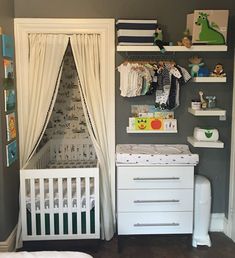 a baby's room with a white crib, dresser and shelves on the wall