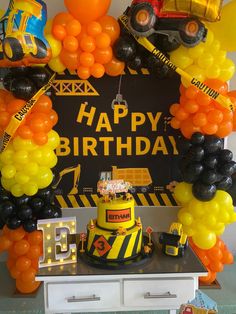 a construction themed birthday party with yellow and black balloons, trucks and cars on the wall