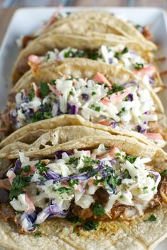 three tacos on a plate with cole slaw and cilantro in the middle