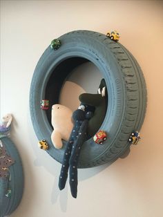 there is a stuffed bear and toy cars in the tire shaped wall hanging on the wall