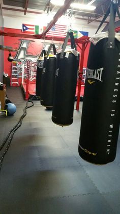 an indoor gym with punching bags hanging from the ceiling and ropes in front of it