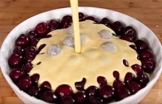 a bowl filled with cherries and cheese being drizzled on top of it