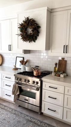 a kitchen with white cabinets and a wreath on the wall above the stove top oven