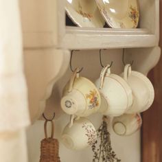 tea cups and saucers are hanging on the wall