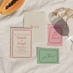 the wedding stationery is laid out on top of the table with fruit and paper