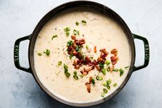 a pot filled with soup sitting on top of a white counter next to a spoon