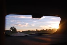 the sun is setting in the distance as seen from inside a car