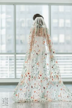 a woman in a white wedding dress with flowers on the back and veil over her head