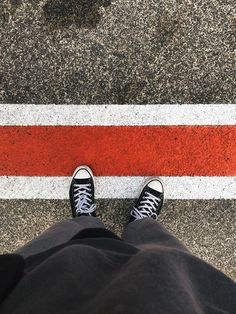 a person standing in front of a red and white stripe on the ground with their feet up