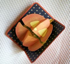 an origami flower sitting on top of a blue and white plate with polka dots