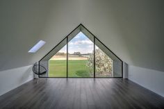 an empty room with large windows and wooden flooring is seen from inside the building