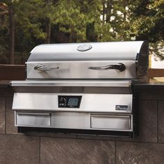 an outdoor bbq grill with two burners on the outside wall and trees in the background