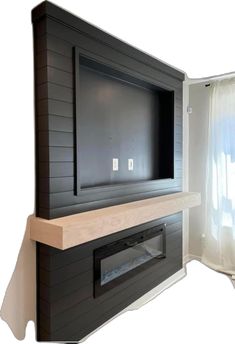 a flat screen tv mounted to the side of a wall next to a curtained window