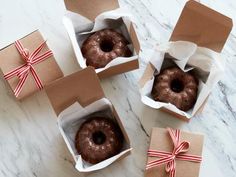 three donuts wrapped in brown paper and tied with red ribbon