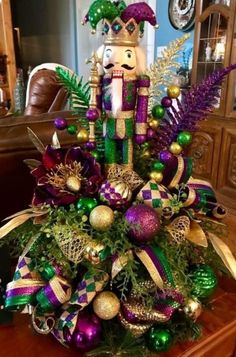 a nutcracker centerpiece is adorned with green, purple and gold ornaments