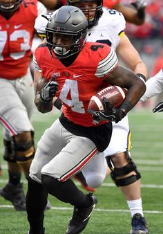 a football player running with the ball in his hand and other players on the field behind him