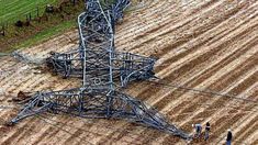 two men are working in the middle of a plowed field with power lines attached to it