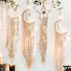 three white dream catchers hanging from the side of a wall with greenery on them