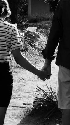 a man and woman holding hands walking down a path