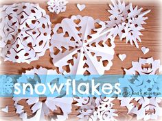 paper snowflakes on a wooden table with the words snowflakes written below