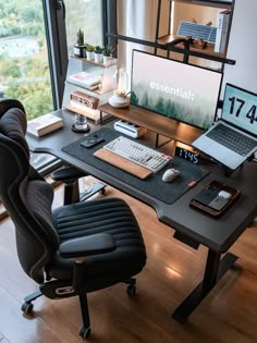 a computer desk with a laptop, keyboard and mouse on it in front of a large window