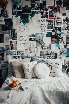 a white bed topped with lots of pillows and pictures on the wall next to it