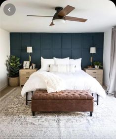 a bedroom with a bed, ottoman and ceiling fan