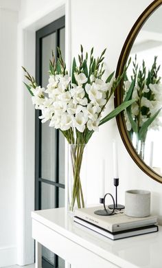 a vase with white flowers sitting on top of a table next to a mirror