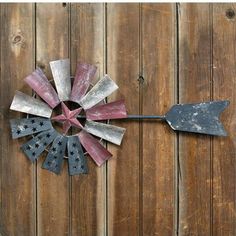 an old metal windmill is hanging on a wooden fence with stars and stripes painted on it