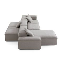 a gray sectional sofa with pillows on the top and bottom, sitting in front of a white background