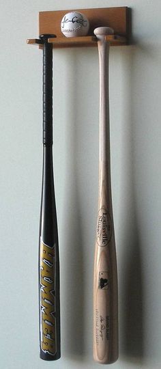 three baseball bats are hanging on the wall next to a bat holder with a ball and bat in it