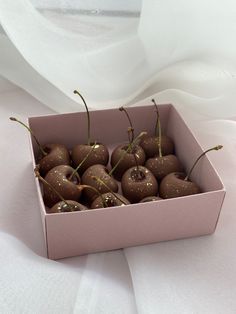 a pink box filled with chocolate covered cherries on top of a white table cloth