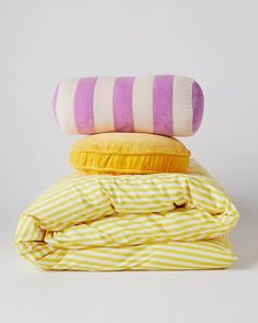 three pillows stacked on top of each other, one yellow and the other white with stripes