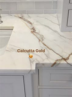 a white marble counter top with the words calcutta gold on it's side