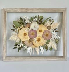 an arrangement of flowers in a wooden frame