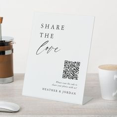 a white sign sitting on top of a wooden table next to a cup and saucer