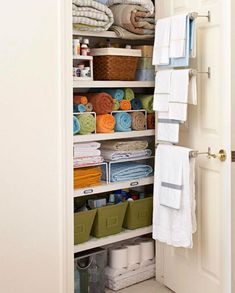 an organized closet with folded towels and other items in the door open to reveal storage