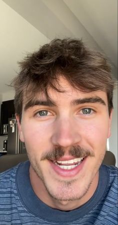 a close up of a person with a moustache on his face and blue shirt