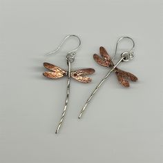 "Dragonfly earrings done in sterling silver & flame patinaed copper. Wings measure approx. 1\" wide and length including earwire is approx. 2 1/4 inch (give or take a bit on the length). Sterling earwires & dragonfly body, copper wings. Flame patina on the copper will vary! These have turned out to be one of my most popular earring creations! due to the hand made nature of these, each earring itself is individually made by hand, there may be slight variances between the photographs and the earri Hand Forged Rose Gold Sterling Silver Earrings, Soldered Copper Earrings As A Gift, Hand Forged Silver Copper Earrings, Nickel-free Rust Drop Earrings, Unique Silver-colored Copper Earrings, Artistic Silver-colored Copper Earrings, Artistic Silver Copper Earrings, Unique Rust-colored Earrings With Ear Wire, Hammered Silver Earrings Made Of Copper