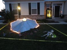 a white umbrella sitting on top of a lush green field next to a house at night