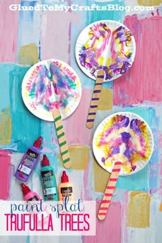 three paper plate crafts with paint and glue on them