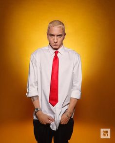 a man with blonde hair wearing a white shirt and red tie, standing in front of an orange background