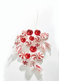 a red and white ornament with candy canes hanging from it's side