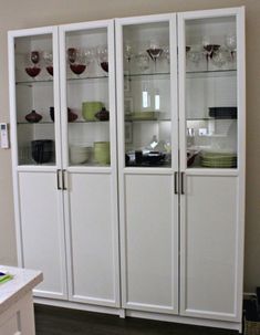 a white china cabinet with glass doors and shelves