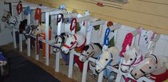 a row of horse heads mounted to the side of a wall next to a white fence