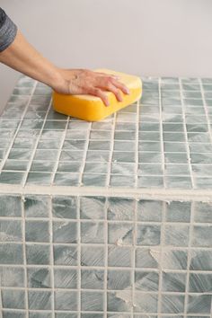 a person with their hand on a sponge that is sitting on top of a table