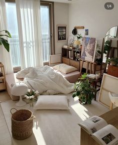 a living room filled with lots of furniture and plants on top of the floor next to large windows