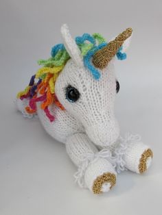 a white knitted stuffed unicorn with multicolored hair