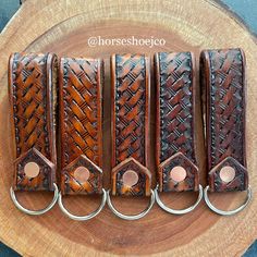 four brown leather bracelets are sitting on a piece of wood with metal rings around them